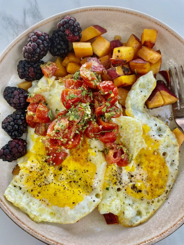 Breakfast bowl: arugula pesto tossed with tomatoes, alongside eggs, sweet potatoes and blackberries.