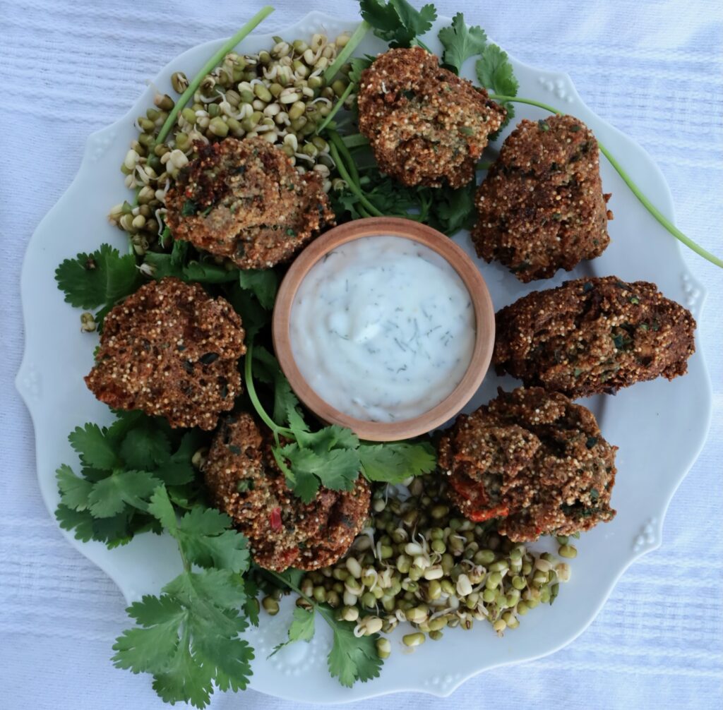 a circle of amaranth puffs surrounds a bowl of dill yogurt....garnished by some mung beans and cilantro.