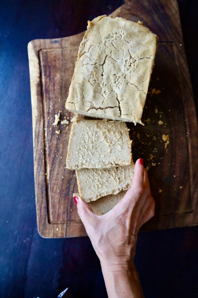 a graceful hand with red painted nails reaches for a slice of fresh cut bread