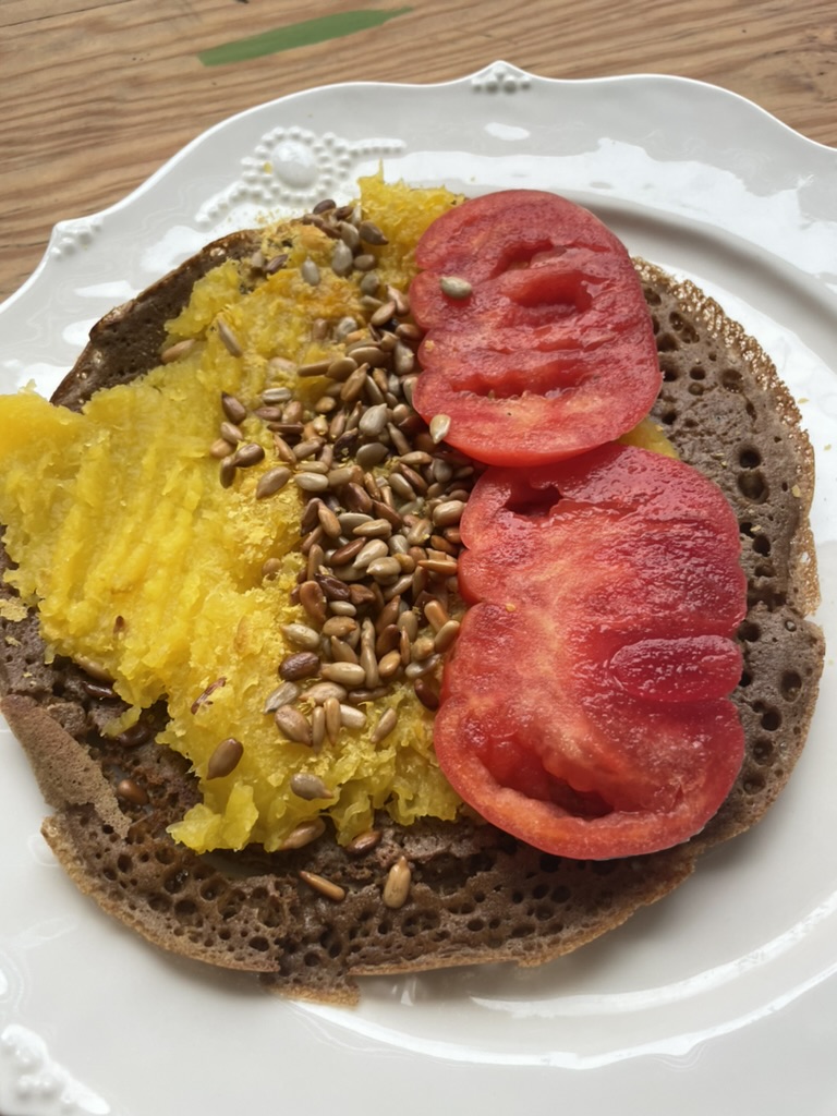 An almond teff wrap is filled with roasted butternut squash, toasted sunflower seeds, and tomatoes.