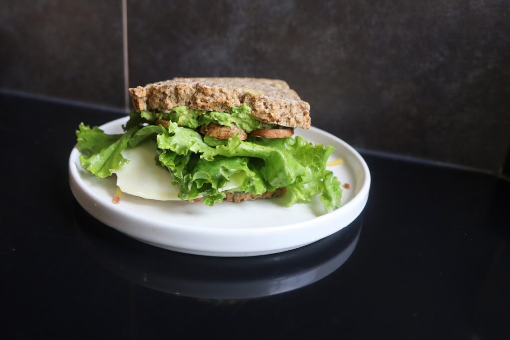 A egg, avocado, mushroom and lettuce sandwich on chia bread that is gluten free. 