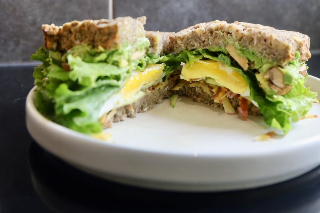 a sandwich made with chia bread is cut in half showing the egg and vegetables