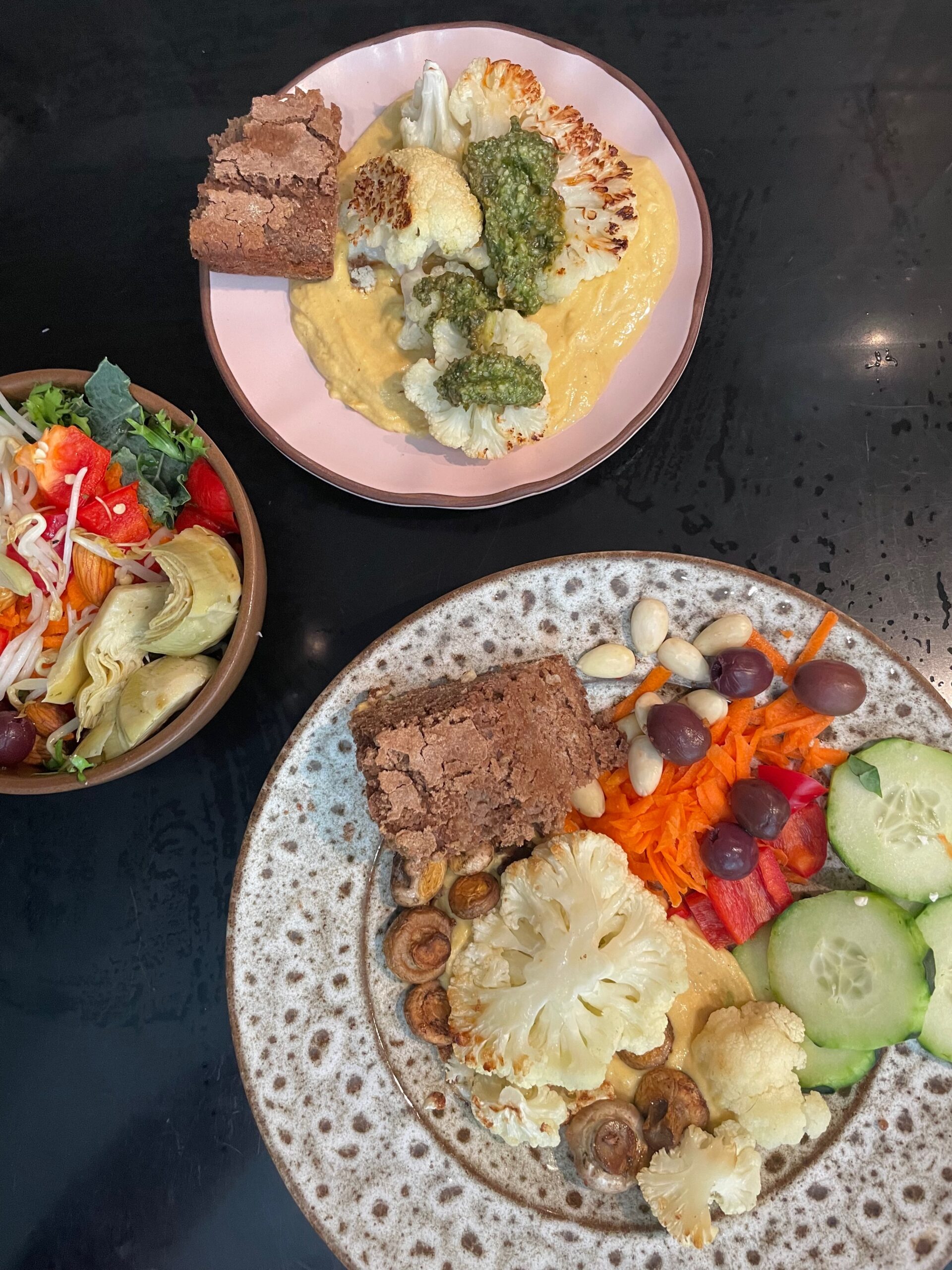 3 plates of various vegetables and a big chunk of quinoa vegan bread