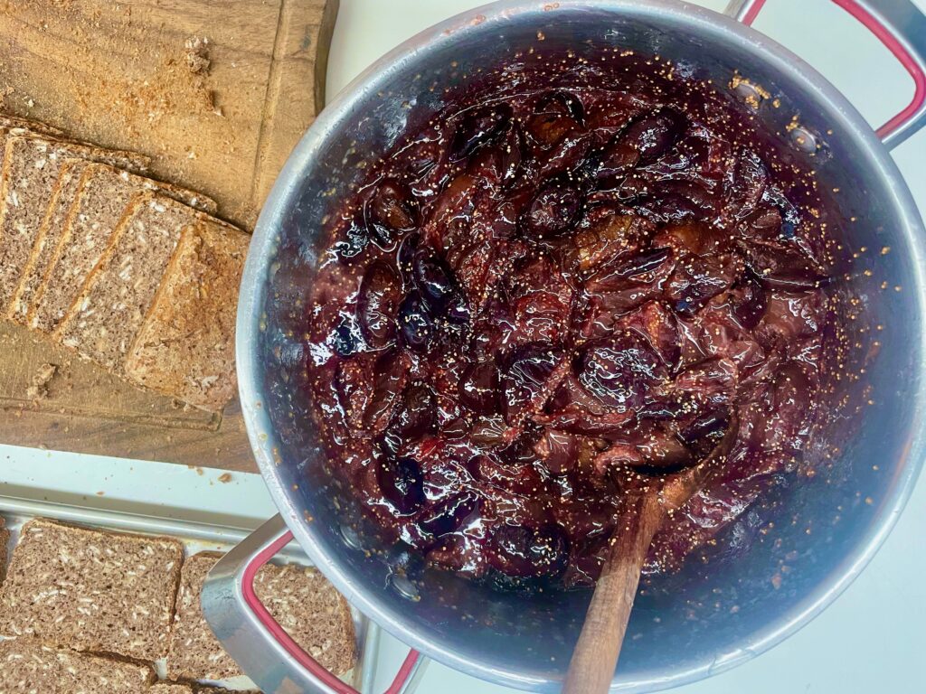 a pot of sugar-free fig preserves has a wooden spoon and is next to sliced Kid's Gluten-Free Seed Bread