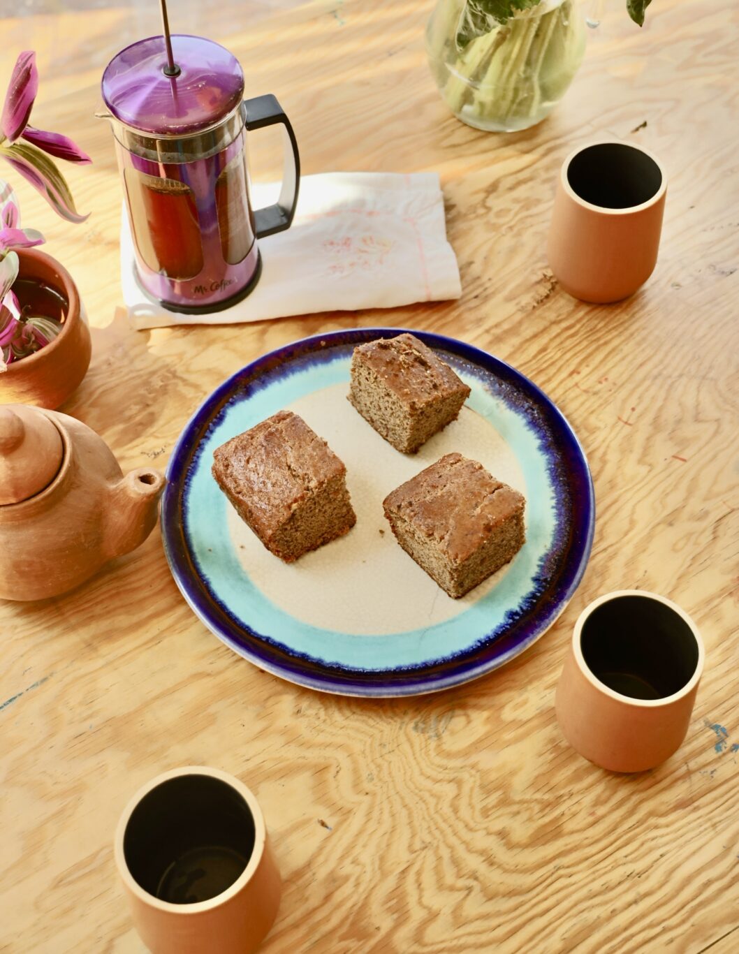 three pieces of protein banana bread is on a large plate surrounded by 3 coffees...