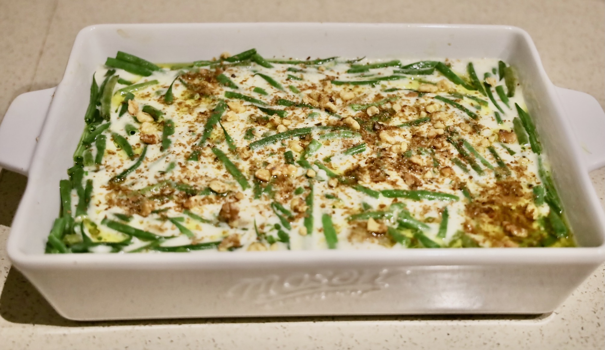 Dairy Free Green Bean Potato Casserole Prep Time: 1 hour Cook Time: 50 minutes _ This is far from your typical Durkee Green Bean Casserole; it's a unique, soup-free green bean casserole. A friend once remarked, “Why would anyone opt for the traditional Durkee green bean casserole, a standard in American cuisine, when they could have this? This is the best thing I've ever eaten.”_ The classic Durkee green bean casserole, while a staple of many tables, is laden with preservatives from canned mushroom soup, saturated in sodium, and carries unhealthy fats courtesy of the fried onions. Its nutritional value is minimal, leaving much to be desired, especially in an era where access to high-quality foods has significantly improved, diminishing its appeal to many. Conversely, a homemade version of this casserole elevates the dish to new heights of health and flavor. Utilizing goat's milk for its better digestibility or coconut milk for a dairy-free alternative, this casserole marries the nutritional benefits with gourmet taste. It boasts organic French green beans known for their tender texture, vibrant, life-enhancing mushrooms and shallots, and a rich, scratch-made béchamel sauce that replaces the canned soup. The addition of organic potatoes not only infuses the dish with more substance but also introduces a universally beloved element. This homemade green bean casserole is so delightful, it stands proudly as a standalone dish, ready to impress guests with its depth of flavor and wholesome ingredients. Incorporating potatoes not only adds heartiness but ensures its place as a crowd-pleaser. _Make this recipe with coconut oil and coconut milk to be a dairy free green bean casserole. Of course, once you remove the dairy, this becomes a vegan bean casserole_