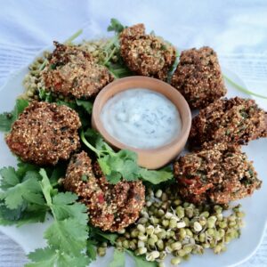 a circle of amaranth puffs surrounds a bowl of dill yogurt....garnished by some mung beans and cilantro.