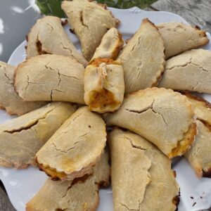 a plate of sweet potato filled empanadas is in front of a cactus leaf in the background