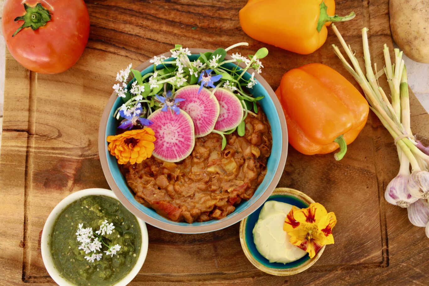 a blue pottery bowl of beans is surrounded by a myriad of gorgeous things...tomatillo salsa, cashew cheese sauce, peppers