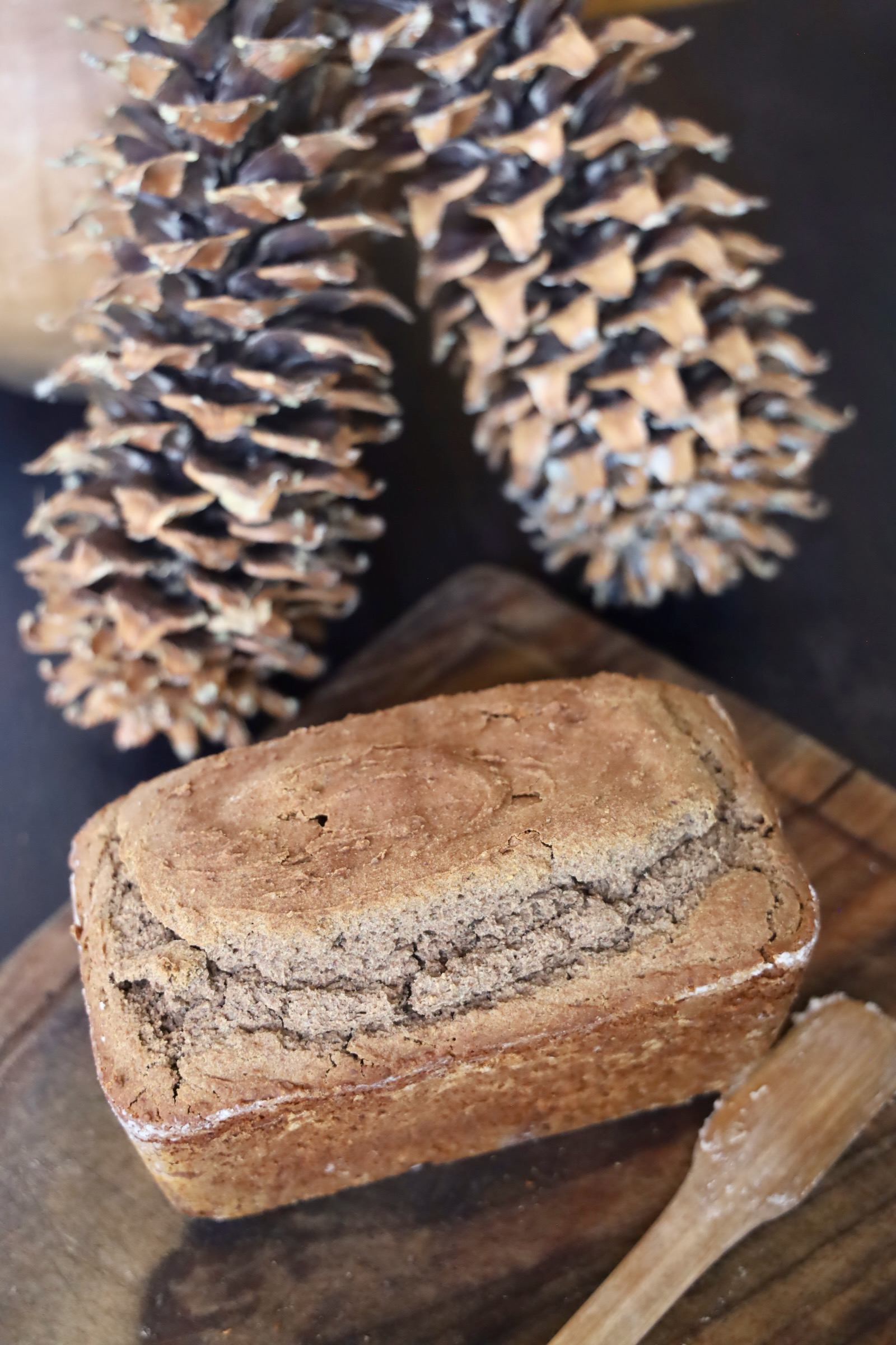 A large loaf of bread is next to a wooden spatula, perfect for removing bread from pans without scratching your bread pan.