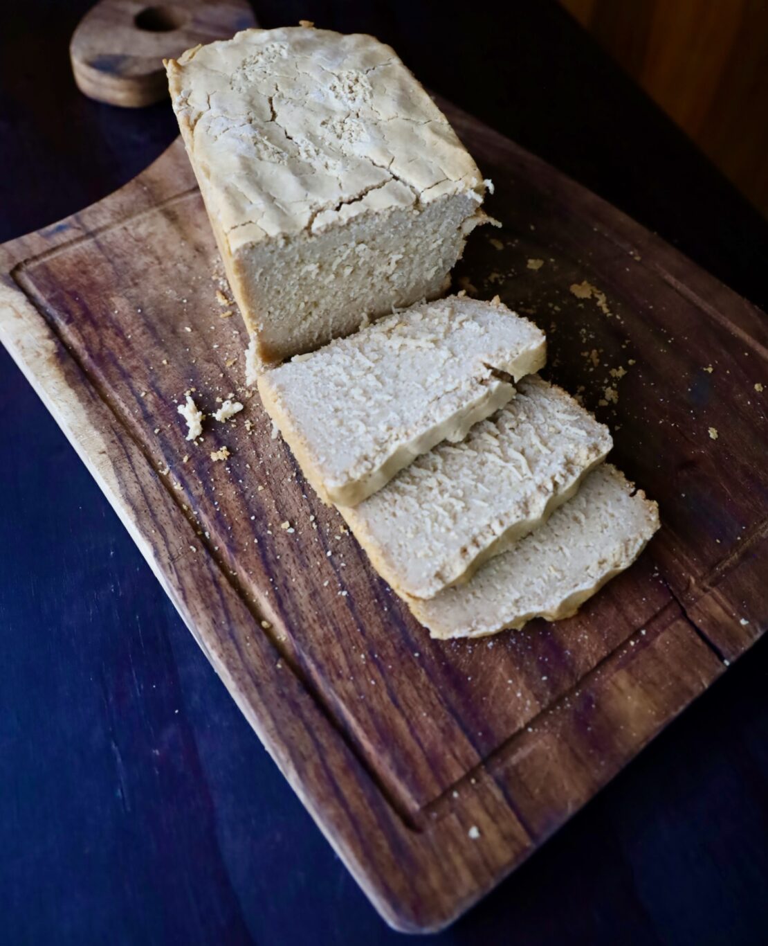 a loaf of white bread has three sliced cut on a cutting board.