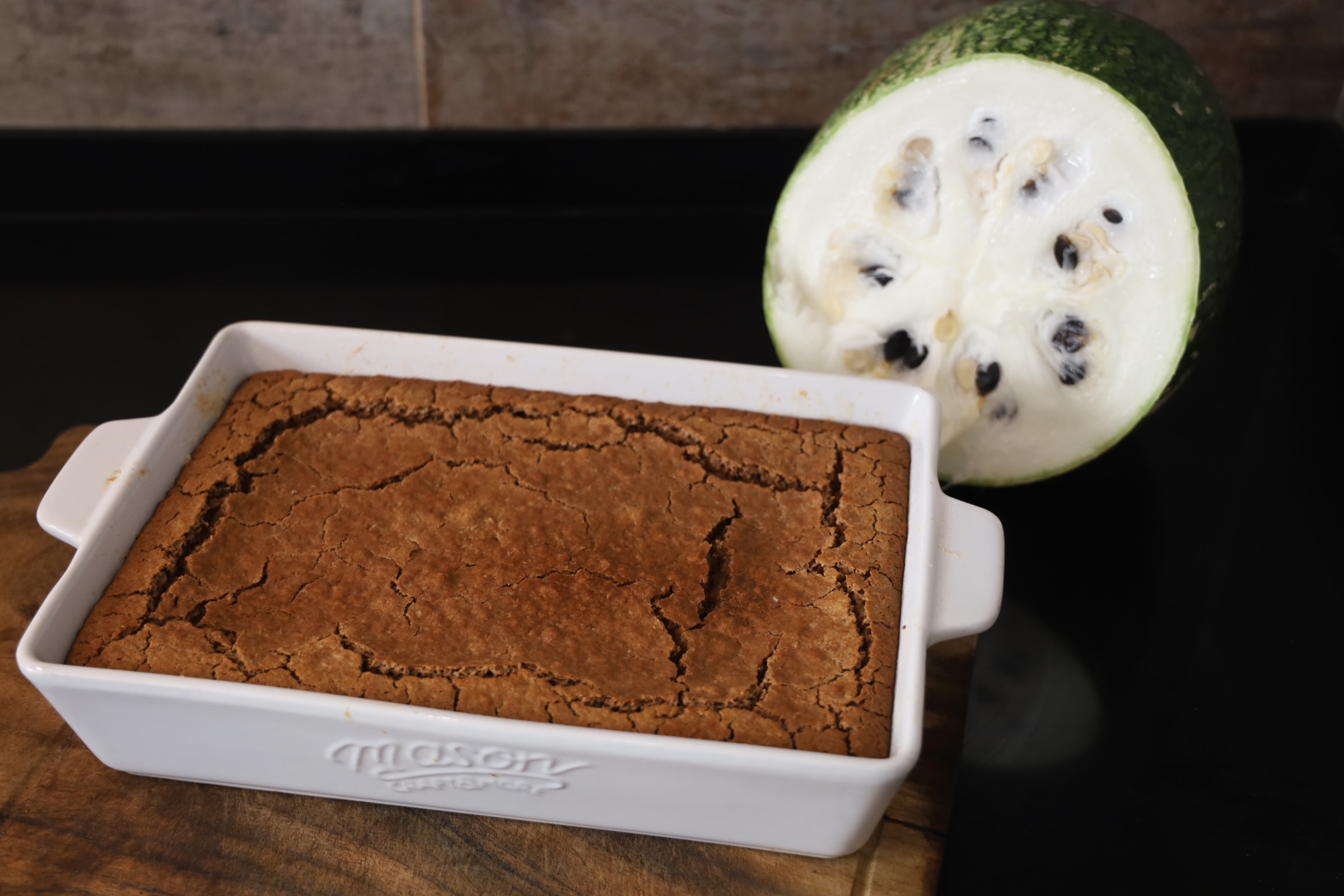 a large quinoa loaf is shown in a mason crockware 8 by 12 dish. A large native squash is shown behind the bread and is featured in the youtube recipe for the soup that goes with this bread.