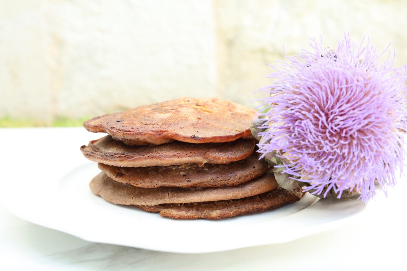 a stack of pancakes rest on a white plate.