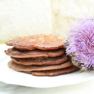 a stack of pancakes rest on a white plate.